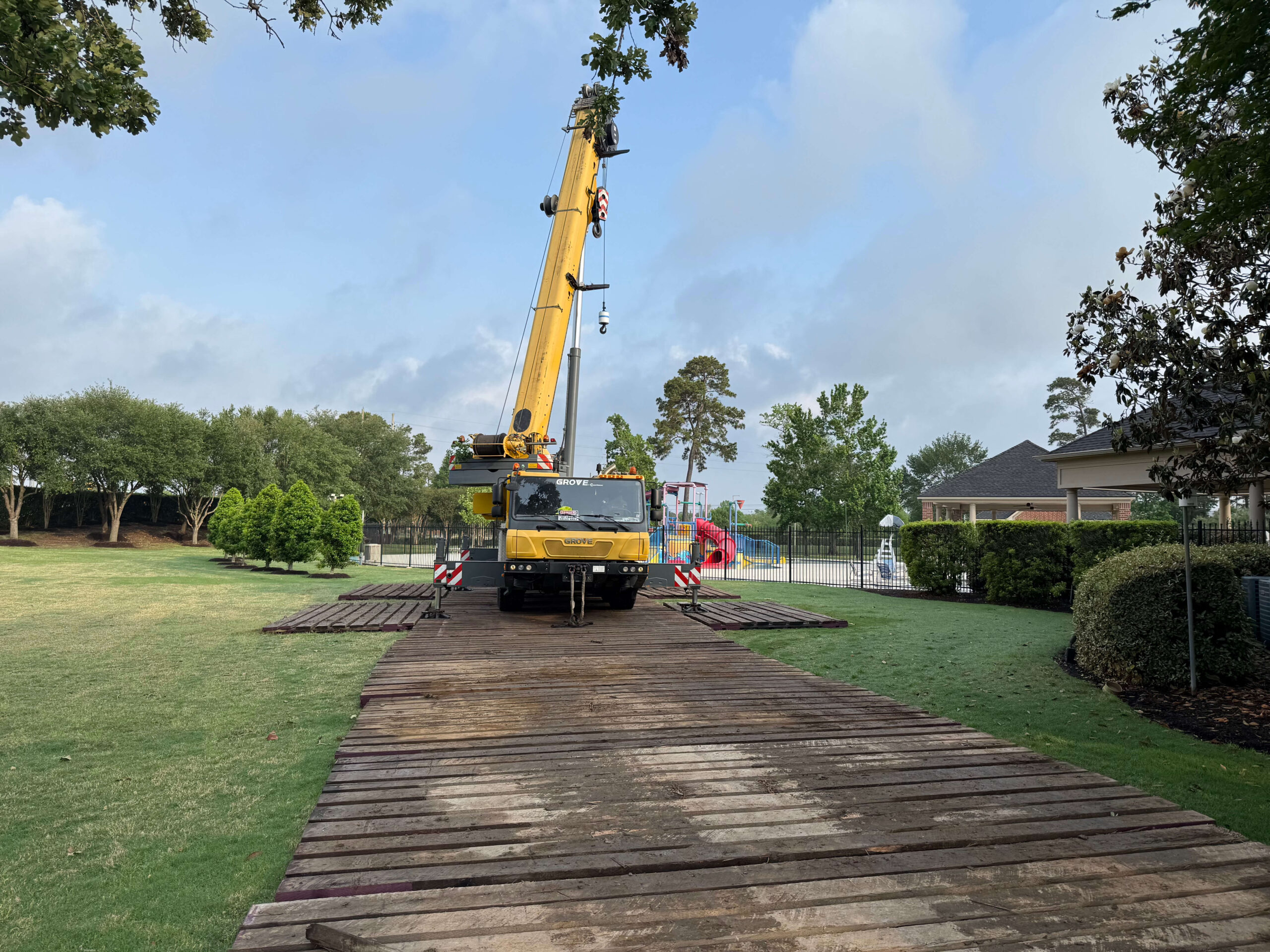 A large yellow crane with 3-ply laminated mats installed beneath it to form a stable, ground protecting support surface while it operates.